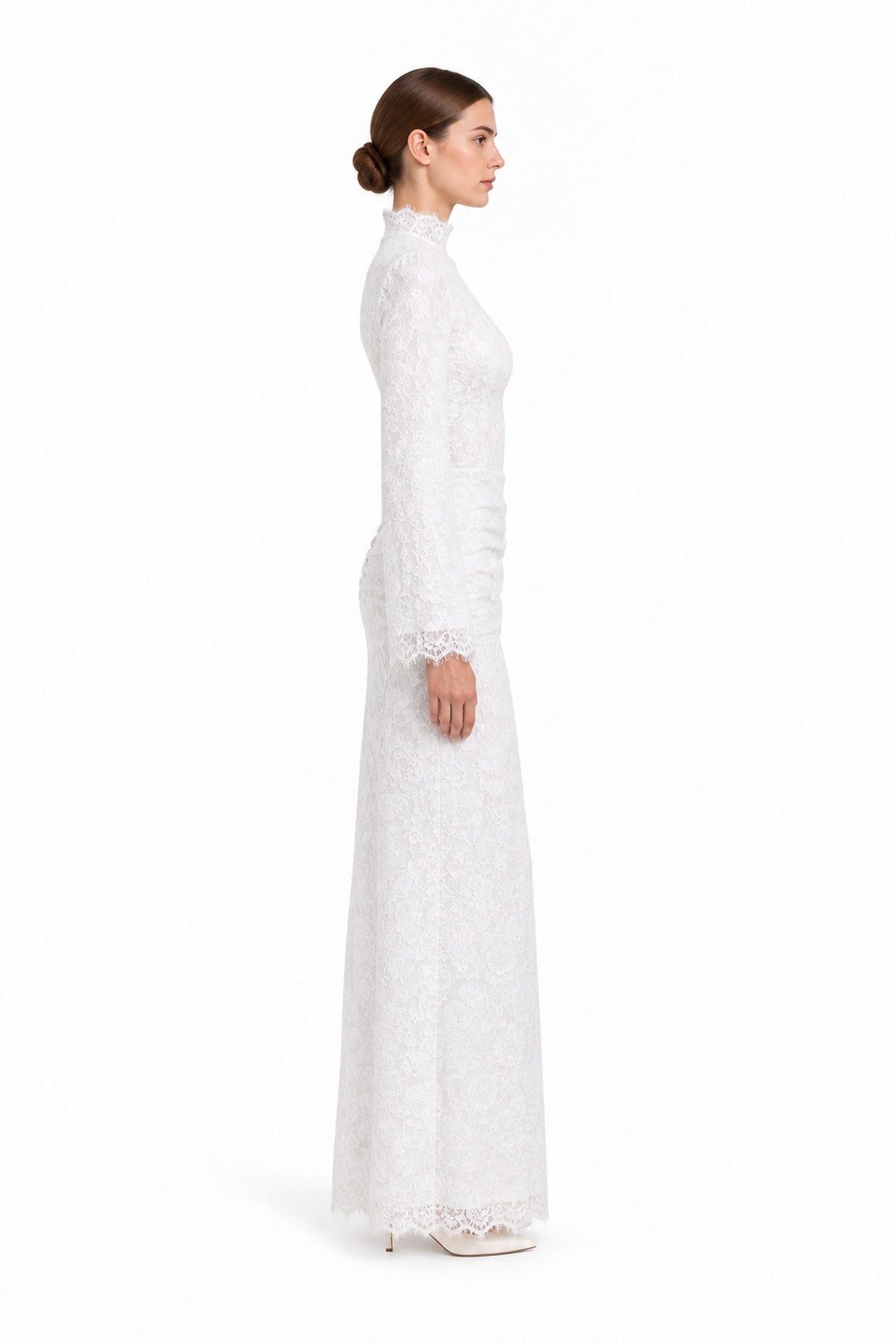 Side studio view of the Lilia white lace dress on a model, showing the high neckline, long sleeves and scalloped hem