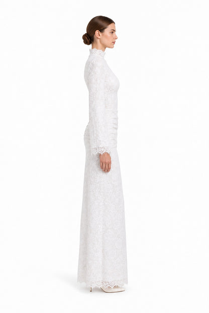 Side studio view of the Lilia white lace dress on a model, showing the high neckline, long sleeves and scalloped hem