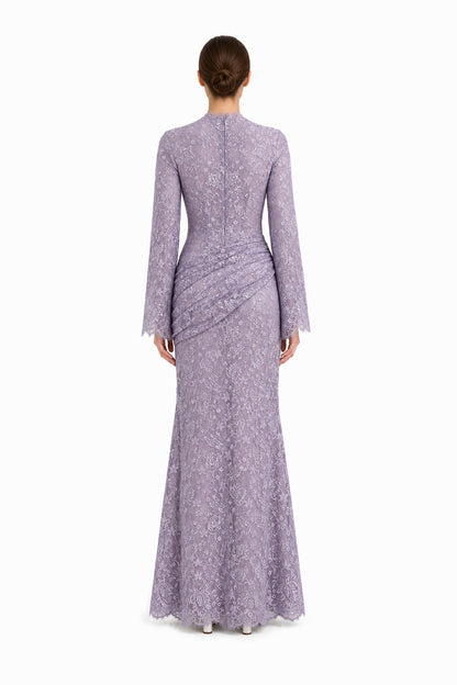 Rear studio view of the Lilia lilac lace maxi dress, showing long sleeves and asymmetric hip draping.