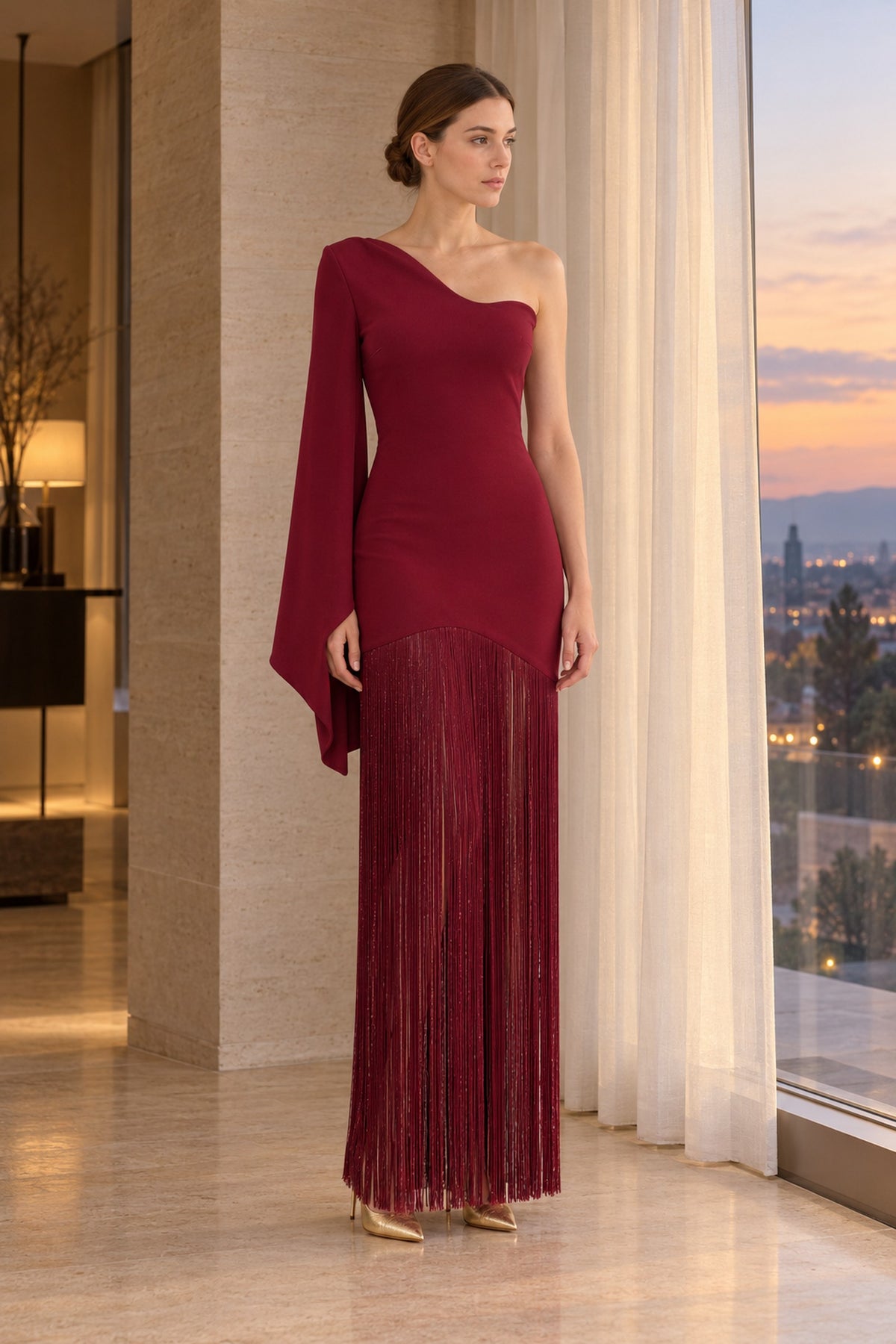 APERLAMIRI Seraphine burgundy one-shoulder cape-sleeve fringe maxi dress — indoor sunset setting